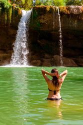 Anonymous female standing near amazing waterfall