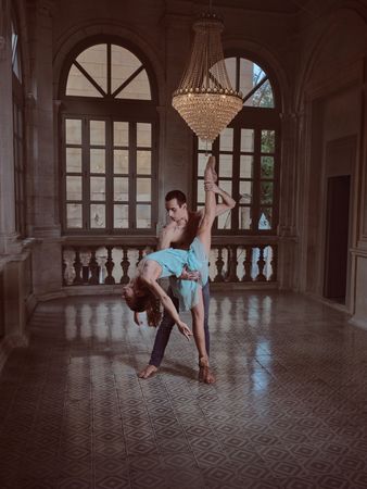 Ballerina doing standing split with help of partner in palace