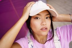 Chinese female looking up at camera near pink wall outside