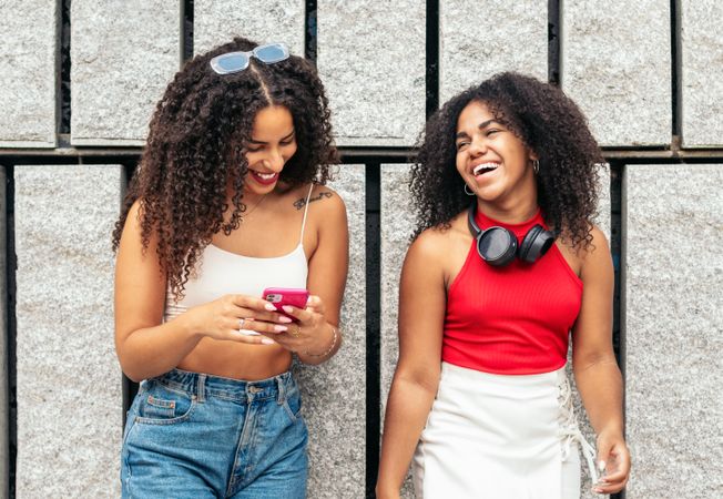 Young people online: female friends using smartphone in the city