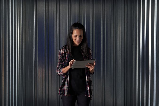 Cheerful woman browsing tablet near storage