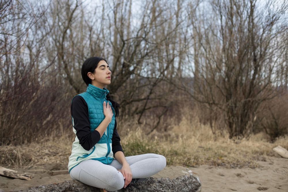 Young female sitting on a log while meditating