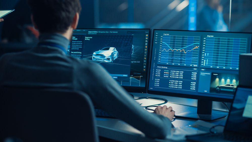 Professional Automotive Graphic Designer is Working on 3D CAD Software Rendering Electric Concept Car and Calculating its Efficiency in a High Tech Innovative Laboratory with a Prototype.