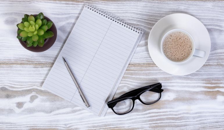Basic stationery with blank notebook and coffee on rustic wooden desk