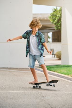 Boy balancing on skateboard on asphalt road