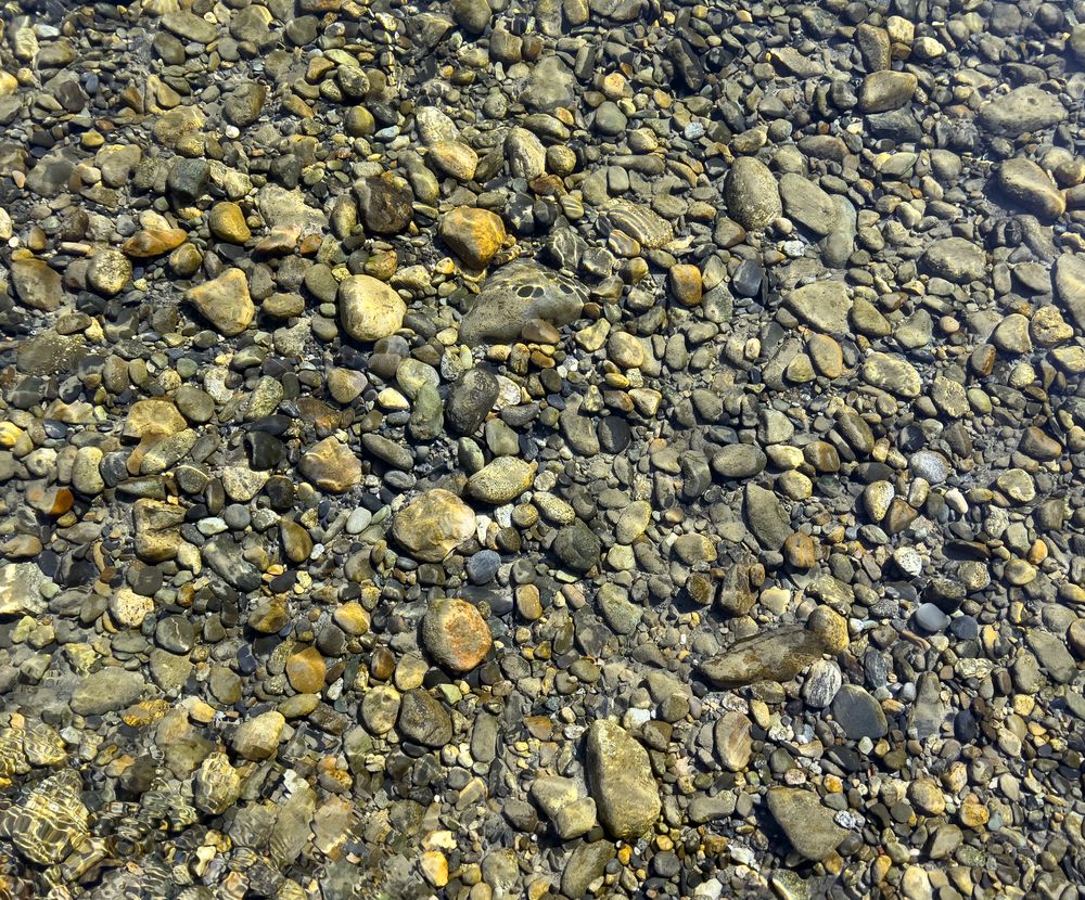 Filled background of river stones under clear water
