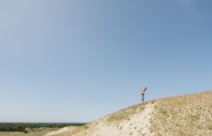 Young woman with rainbow banner against sky