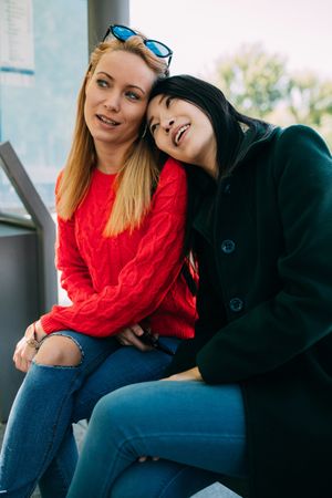 Multiethnic friends sitting on bus stop