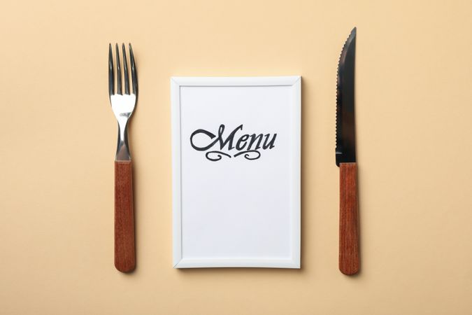 Frame with text Menu and cutlery on beige background