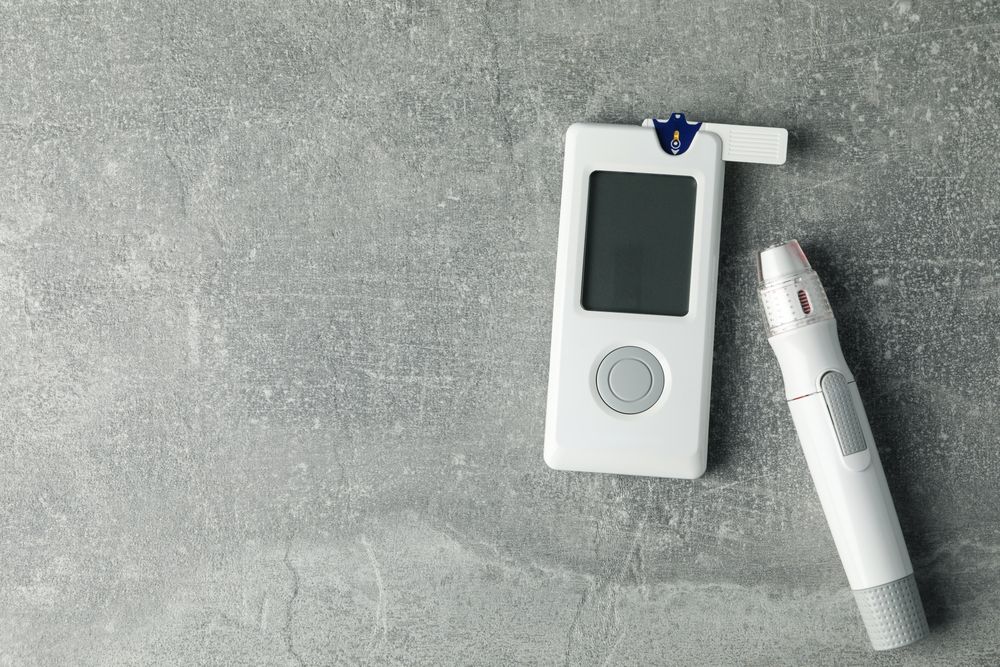 Blood glucose meter on gray background, space for text