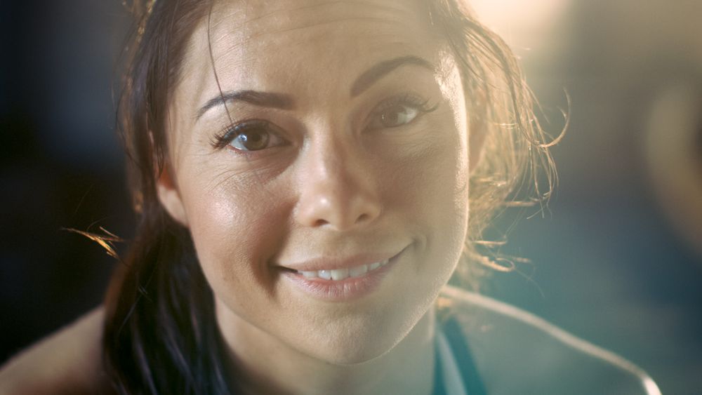 Shot of a Athletic Brunette Resting on the Bench and Smiling into the Camera.