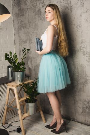 Woman in blue skirt standing beside indoor plant