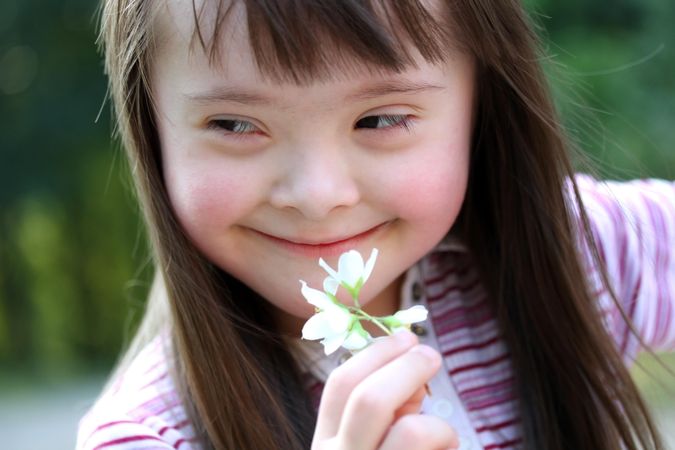 A young girl holding a flower in her hand