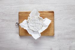 Wheel of brie cheese on wooden board