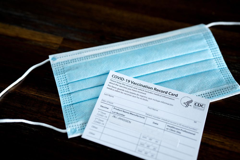 Medical mask and vaccination card laying on table