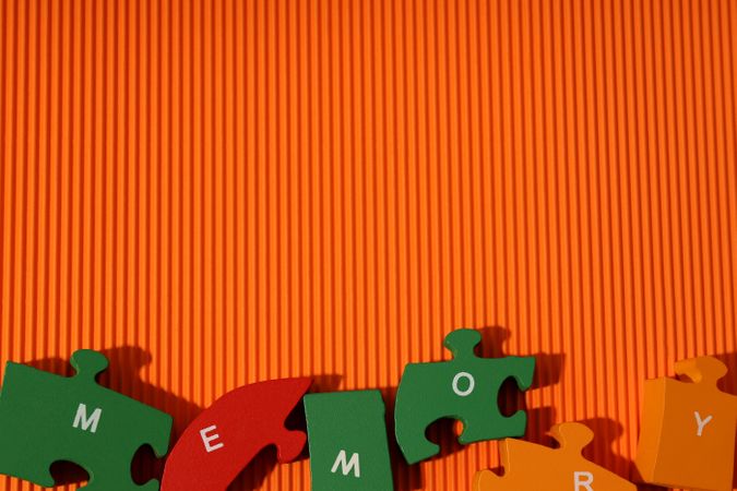 Orange paper background with puzzle pieces spelling out the word “Memory”