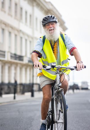 Smiling older man riding bike through town