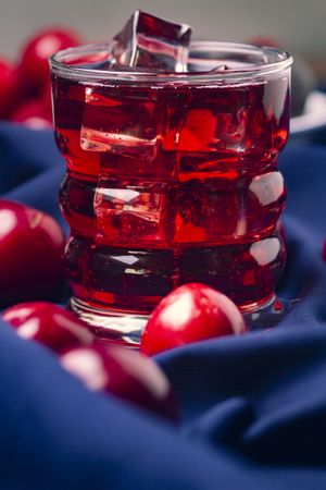 Red beverage near fresh fruits on cloth