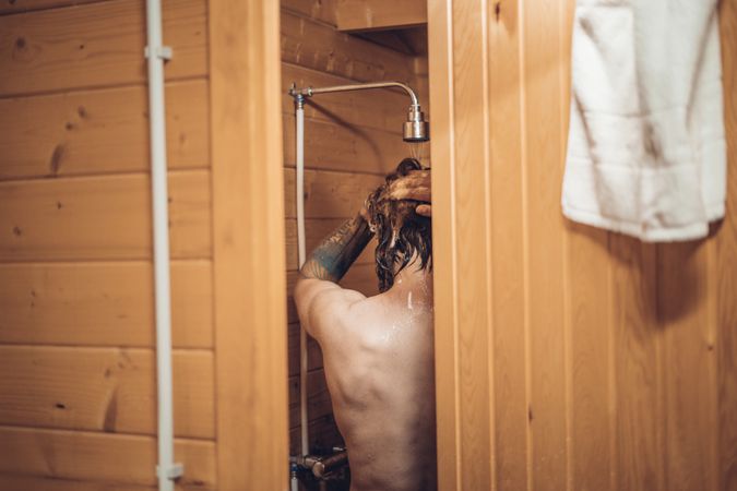 Man taking shower in wooden bathroom