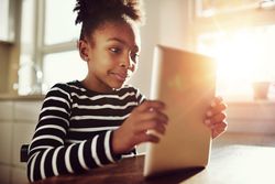 Shot of happy girl watching something on a tablet in a sunny room