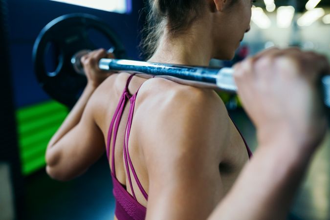 Shot of muscular woman’s back with barbell