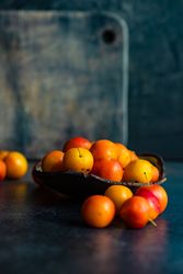 Bowl of plums on dark table