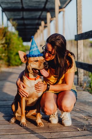 Casual young woman resting next to brown dog with party hat