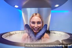 Blonde woman in cryotherapy chamber with gloves on her hand 5RVdW1