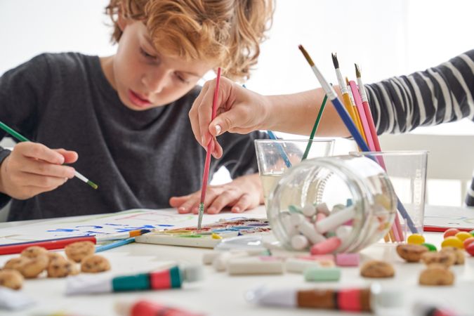 Boy painting near faceless friend