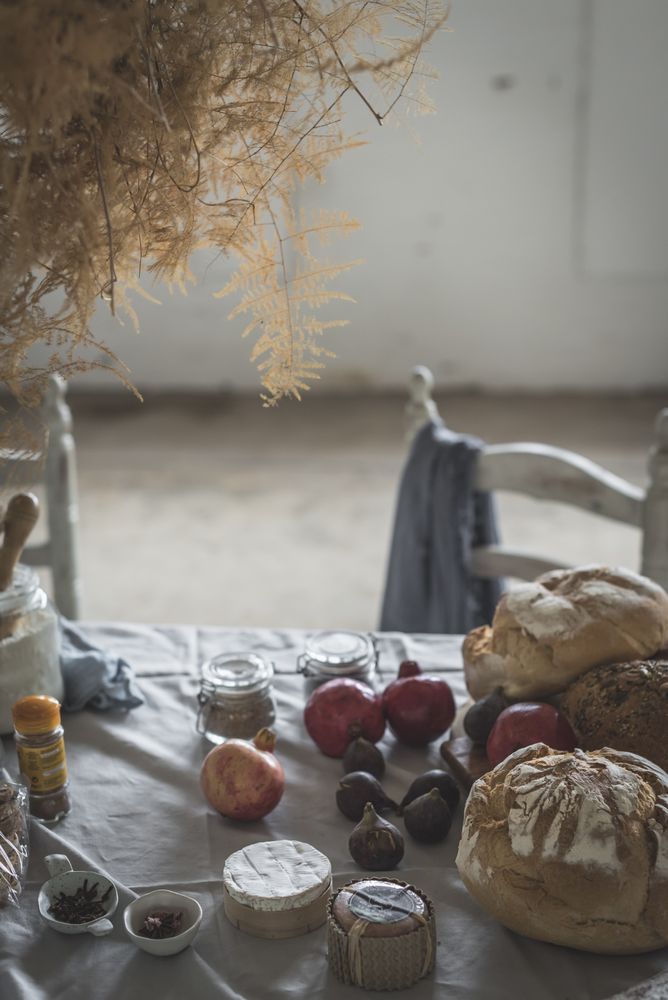 Fresh bread on served table and bunch of dry plant hanging on thread