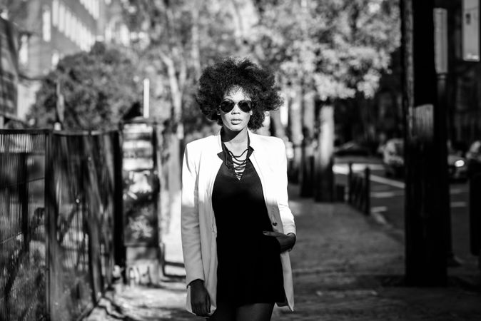Monochrome shot of beautiful woman walking down sunny Spanish street