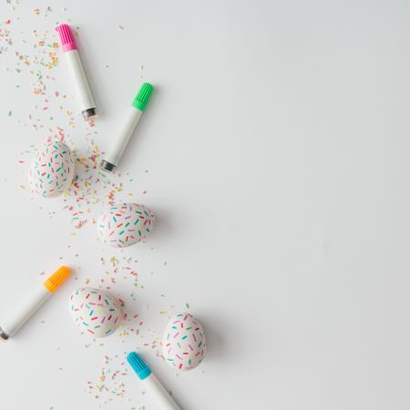 Easter eggs with cake sprinkles and markers on light background