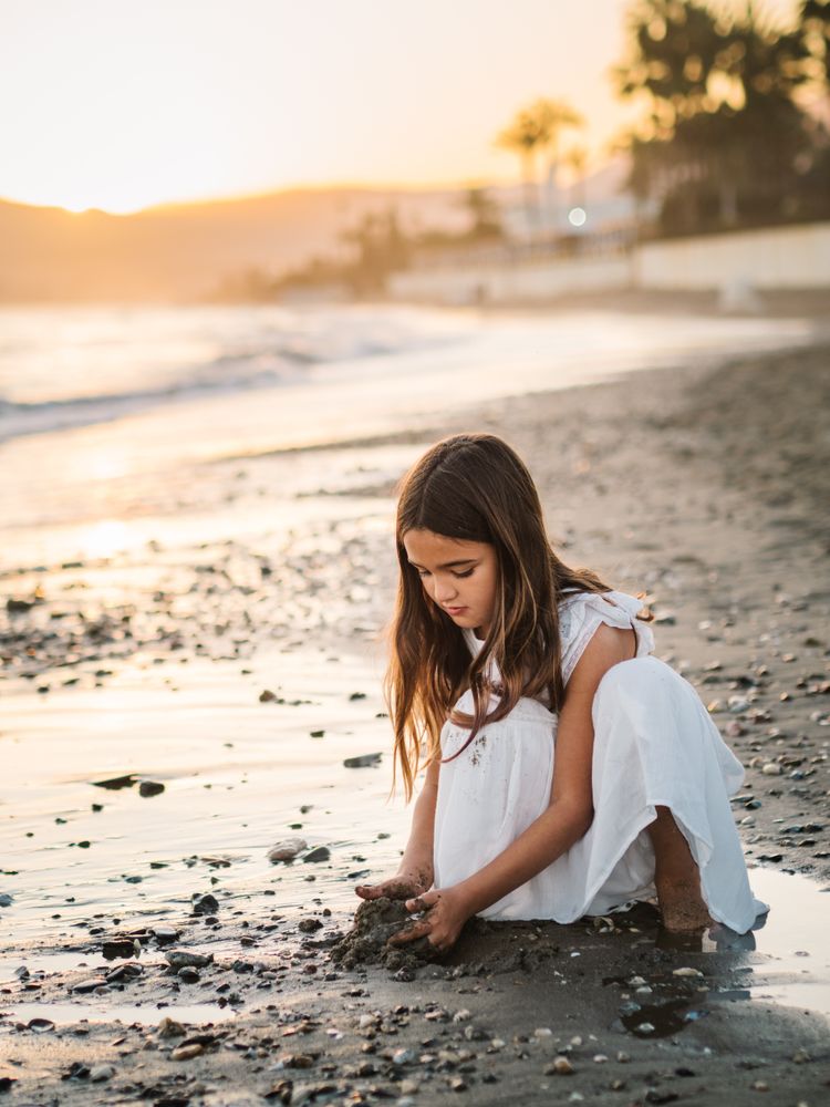 Adorable girl playing with sand on beach