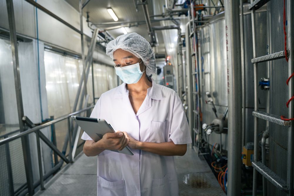 A food factory researcher inspecting canned food conveyor belt machine.