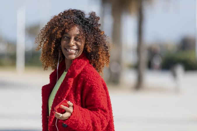 Smiling female in red jacket on street with palm trees