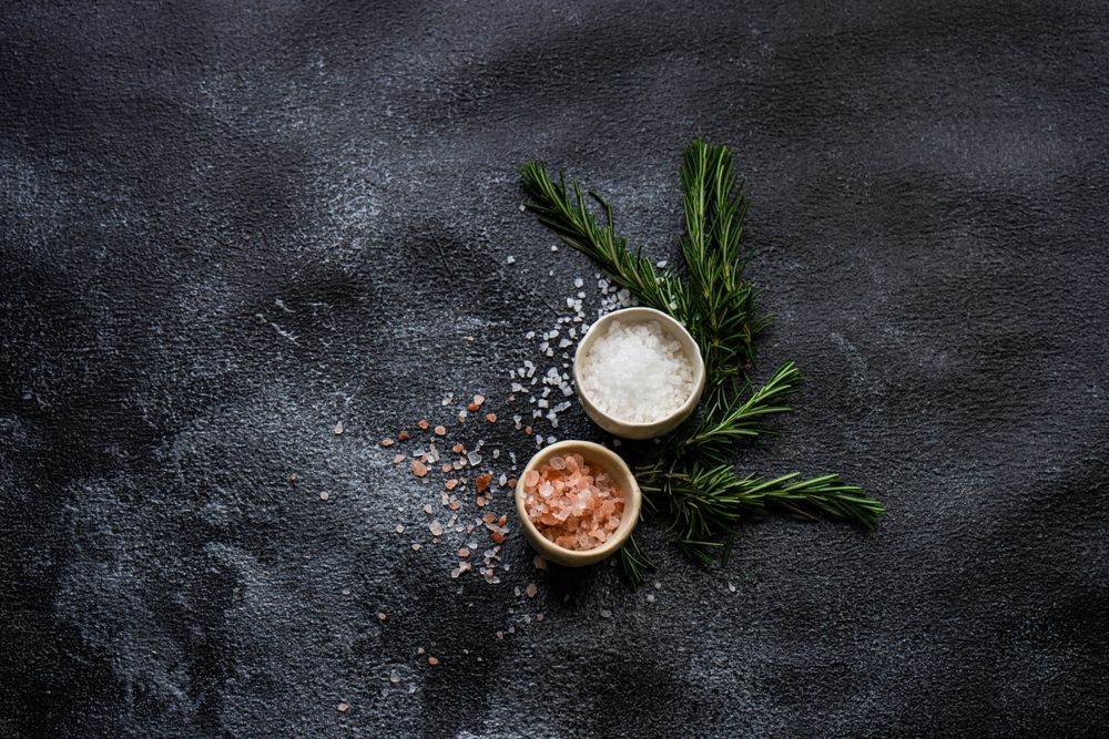 Top view of salt bowls and rosemary on kitchen counter