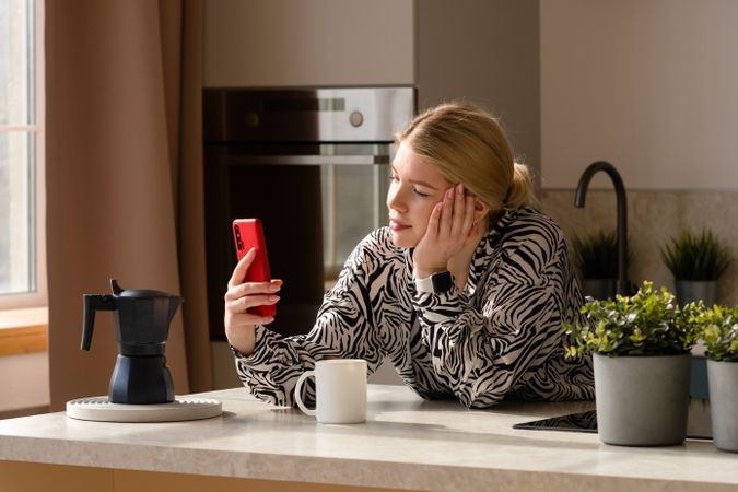 Woman multitasking with phone and coffee.