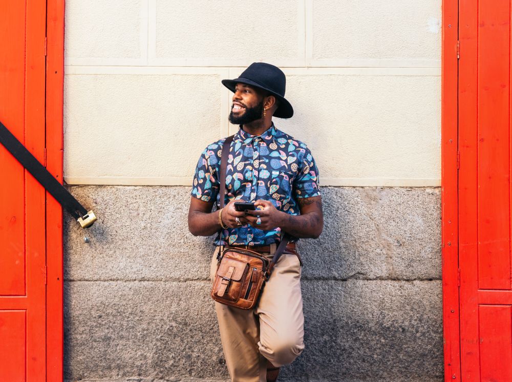 Stylish Black man using smartphone outdoors in the city
