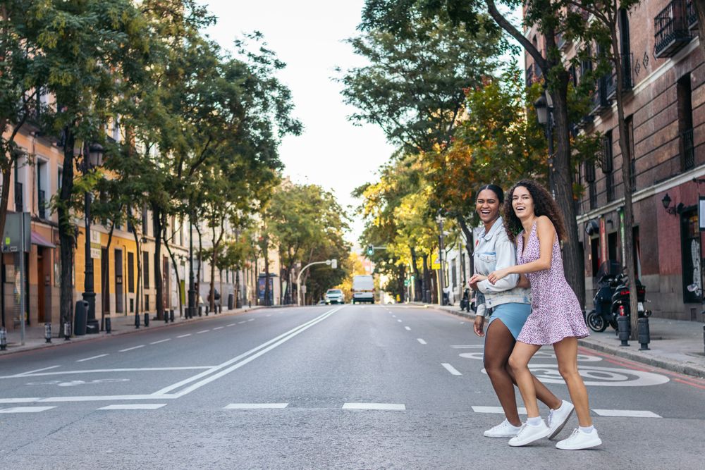 Two women crossing the pedestrian crossing in the city.