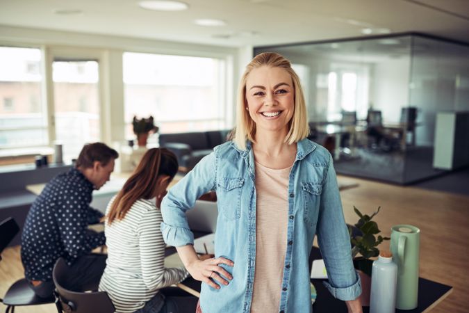 Portrait of blonde business woman smiling in an office with hand on hip