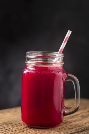 Red beet juice in a glass cup on the wooden table.
