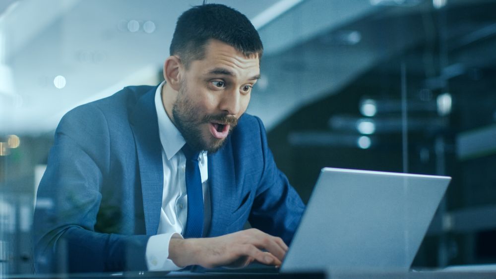 In the Office Businessman Sitting at the Desk Using Laptop Finishes Project and Wins Big.