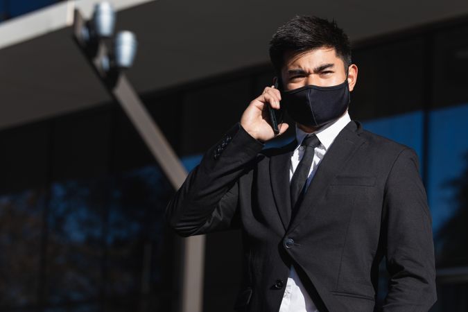 Serious male entrepreneur talking on smartphone in city