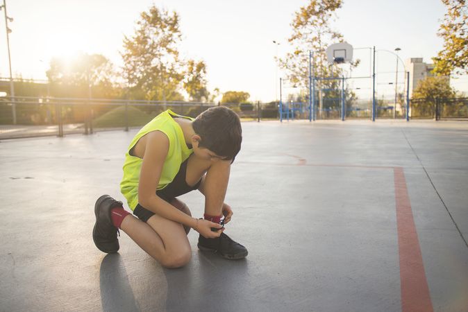 Young man basketball player is tying shoelaces