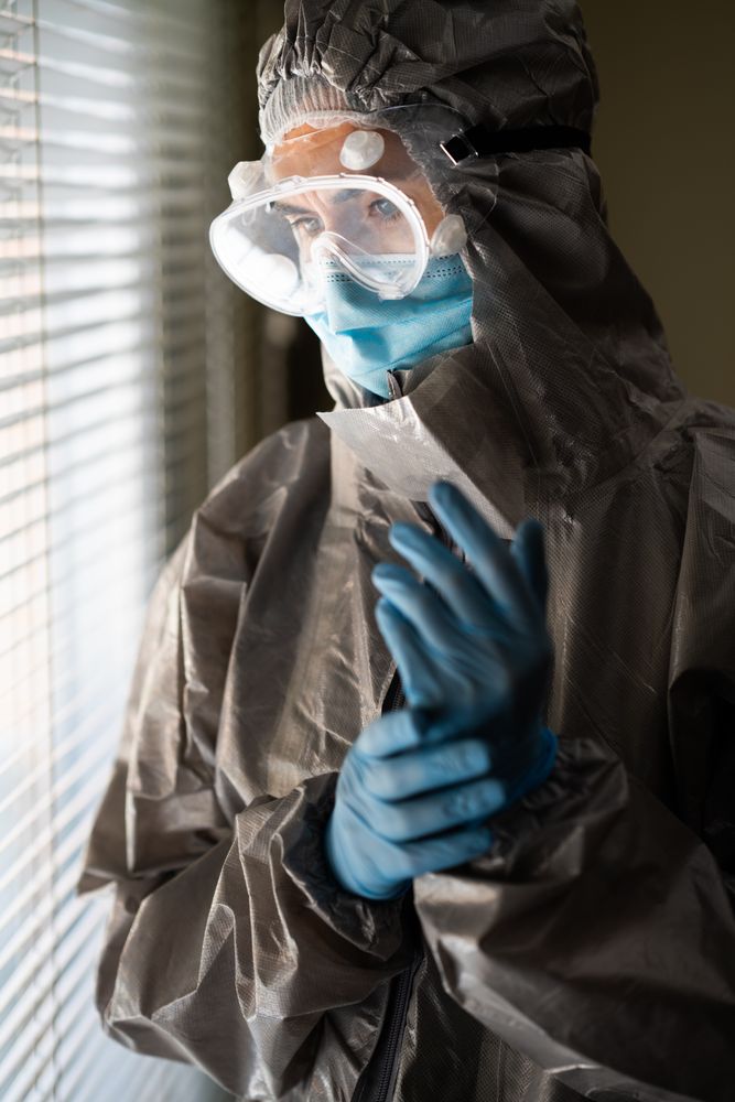 Person in PPE standing beside window