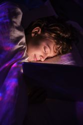 Boy sleeping with tablet in bedroom