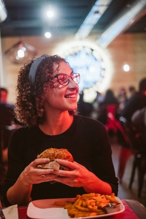 Young woman eating burger in cafe