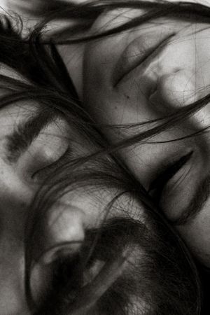 Grayscale close-up shot of man and woman closing eyes and lying side by side in reverse