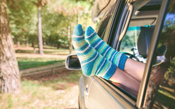 Female legs with socks resting over open window car