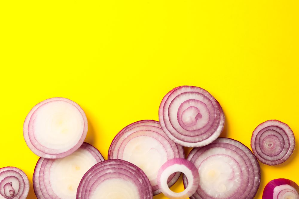 Flat lay composition with red onion rings on color background